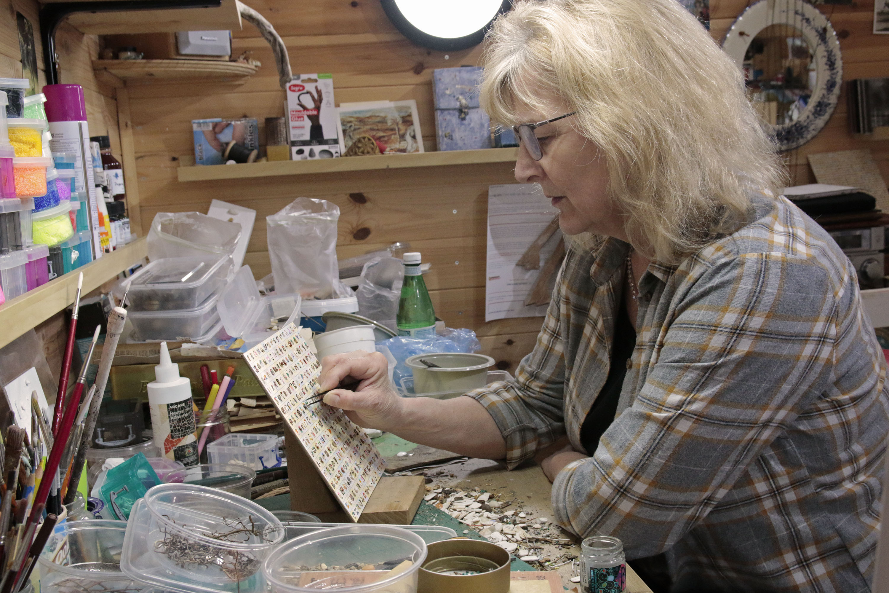 Artist Helen Murray working at her desk on a delicate, small piece. 